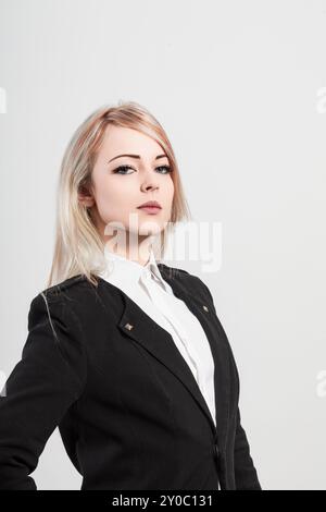 Selbstbewusste junge Geschäftsfrau in schicker Kleidung strahlt Entschlossenheit und Ehrgeiz aus und spiegelt Führungsqualitäten und modernen Stil wider. Ideal für Geschäftsreisen Stockfoto