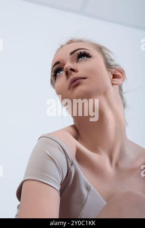 Die entschlossene junge Ballerina dehnt sich in einem Tanzstudio und strahlt Anmut und Kraft aus, während sie ihre Bewegungen mit Hoffnung in ihren Augen übt Stockfoto