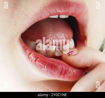 Nahaufnahme eines Fingers, der einen verlorenen Zahn im Mund eines kleinen Mädchens spürt Stockfoto