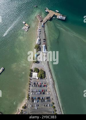 Ein Drohnenschuss von oben, der direkt auf die Sandspit Marina in Auckland, Neuseeland, blickt. In der Aufnahme sehen Sie einen Parkplatz und das Meer Stockfoto