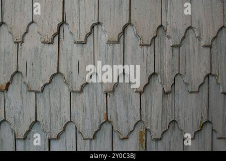 Graue abblätternde Farbe auf Holzschindeln, alte Hausfassade, abstrakte Textur Stockfoto