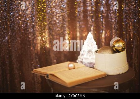 Kleine Box mit viel Weihnachten silbernen und goldenen Verzierungen in der Nähe der Weihnachtsbaum leuchtet und das Buch mit kopieren. Weihnachten Konzept Stockfoto