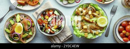 Panorama mit frischen Salaten, Flachbild-Lay-Shot von einer Auswahl. Auswahl an Tellern und Schüsseln mit grünem Gemüse. Gesundes Essen, Top-Shot, Panorama B Stockfoto