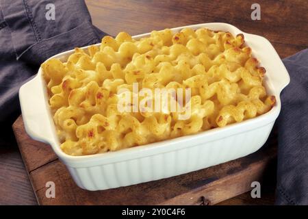 Makkaroni und Käse Nudeln in einem Auflauf, auf einem rustikalen Holztisch. Traditionelles amerikanisches Komfortessen, Lebensmittelfotografie Stockfoto