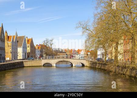 Brügge, Belgien, 10. April 2016: Panorama mit Kanal, Brücke und bunten traditionellen Häusern vor wolkenblauem Himmel im beliebten belgischen Reiseziel br Stockfoto