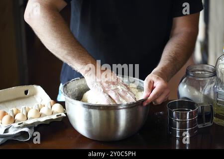 Männliche Hände kneten frischen Teig auf dem Küchentisch. Nahaufnahme Stockfoto