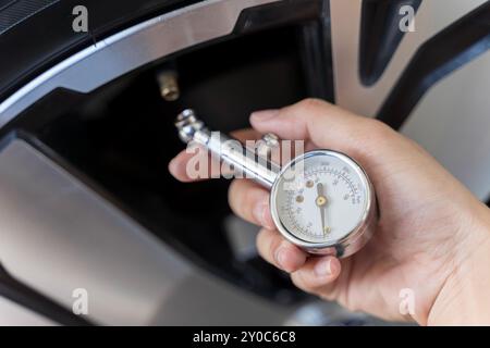 Nahaufnahme eines Reifendruckmanometers an einem neuen Rad in einer Reifenwerkstatt. Handmann, der den Luftdruck des Autoreifens überprüft, den Zustand seines c Stockfoto
