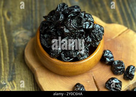 Schwarzer Pflaumenstapel aus einer großen Anzahl reifer Pflaumen, ein Pflaumenstapel auf einem Holztisch in der Küche aus nächster Nähe Stockfoto