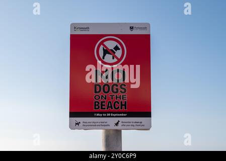 Ein hellrotes Schild am Southsea Beach erinnert die Menschen daran, dass in den Sommermonaten keine Hunde erlaubt sind und nach dem Tier aufräumen dürfen. August 2024. Stockfoto