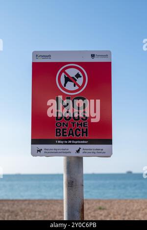 Ein hellrotes Schild am Southsea Beach erinnert die Menschen daran, dass in den Sommermonaten keine Hunde erlaubt sind und nach dem Tier aufräumen dürfen. August 2024. Stockfoto