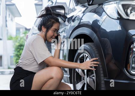 Schöne junge Fahrradmechanikerin, die mit einem Kunden telefonisch spricht. Frau, die Autoreifen mit elektrischer Pumpe auf der Landstraße aufbläst, Wartung und Stockfoto