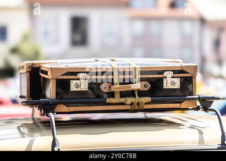 Alte Koffer auf der Motorhaube eines historischen Autos irgendwo in der Stadt. Unterhaltsames Reisekonzept. Stockfoto