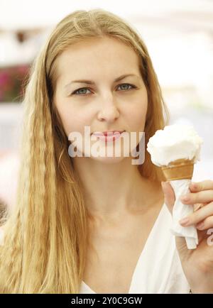 Junge blonde Frau, die draußen Eisbecher in der Hand hält Stockfoto