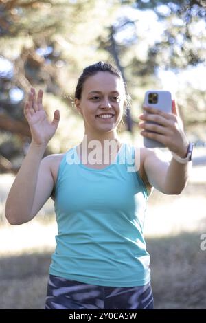 Lächelnde Sportswear-Frau, die mit dem Handy telefoniert, vertikale Nahaufnahme Stockfoto