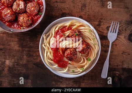 Fleischbällchen. Rindfleischbällchen, oben flach liegend in einer Pfanne und mit einem Teller Spaghetti Pasta, auf einem rustikalen hölzernen Hintergrund, Lebensmittelfotografie Stockfoto