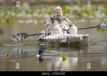 Ein redaktionelles Foto eines Fotografen in einem Kajak, der auf dem Fernan Lake in Nord-Idaho einen Seeteufer fliegt Stockfoto