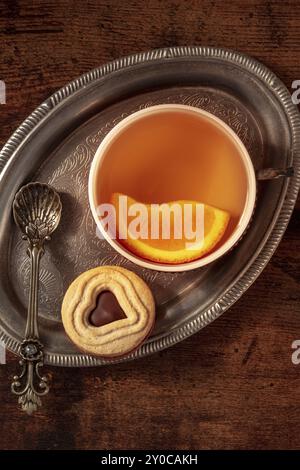 Orangentee mit Keksen, eine Tasse auf einem Vintage-Tablett auf einem dunklen rustikalen Holzhintergrund, von oben aufgenommen, Lebensmittelfotografie Stockfoto