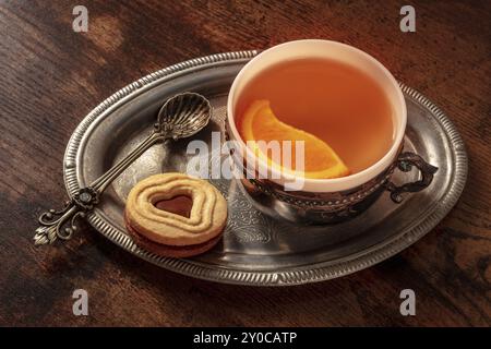 Orangentee mit Keksen, eine Tasse auf einem Vintage-Tablett auf einem dunklen rustikalen Holzhintergrund, Lebensmittelfotografie Stockfoto