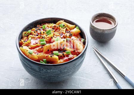 Rabokki, tteokbokki oder Topokki mit Ramen, koreanischem Streetfood, scharfen Reiskuchen, Essstäbchen und einem Getränk, Lebensmittelfotografie Stockfoto