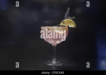 Schicker Cocktail mit frischem Obst. Gin Tonic Drink mit Eis auf einer Party, auf schwarzem Hintergrund. Alkohol mit Lavendel und Zitrone, getöntes Bild, Lebensmittel ph Stockfoto