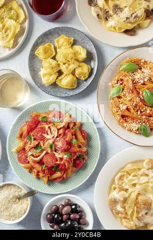 Italienische Pasta, verschiedene Gerichte, Overhead Flat Lay Shot. Spaghetti, Penne mit Huhn, Garnelen-Pappardelle, geriebenem Parmesankäse, Wein und Oliven Stockfoto