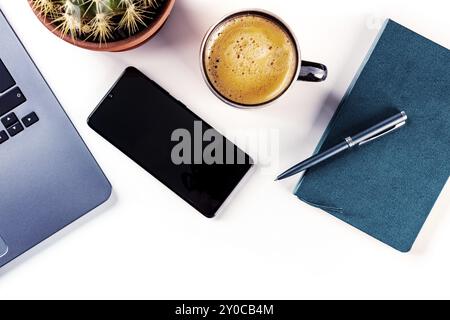 Schreibtisch, Blick von oben auf weißem Hintergrund. Kaffee, Notebook, Telefon, Pflanze und Laptop, Flachbild über dem Kopf. Arbeitslayout mit Kopierbereich Stockfoto