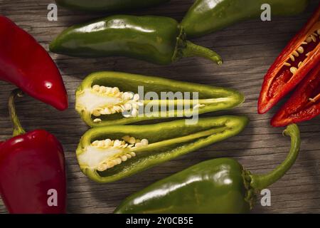 Eine Übersicht über ganze und geschnittene rote und grüne Paprika auf Holz Stockfoto