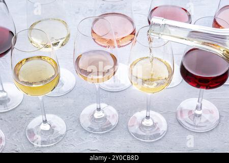 Wein in ein Glas bei einer Verkostung gießen. Rosen-, Rot- und Weißwein, Drinks auf einem Tisch in einem Weingut. Eine Auswahl an Weinen in vielen verschiedenen Farben, Food p Stockfoto