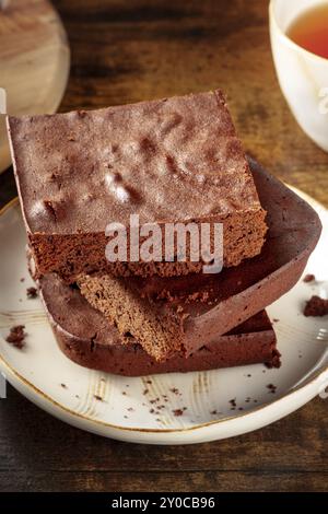 Schokoladen-Brownie mit Tee-Nahaufnahme, einfacher Kaffeekuchen, auf einem dunklen rustikalen hölzernen Hintergrund, Gourmet-Frühstück, Lebensmittelfotografie Stockfoto