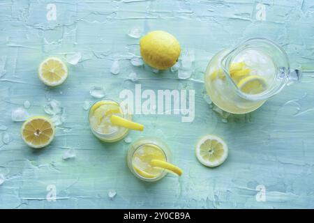 Limonade. Zitronenwasser mit Eis, zwei Gläser und ein Krug auf blauem Hintergrund, über Kopf liegender Schuss. Entgiftungsgetränk. Frischer hausgemachter Cocktail Stockfoto