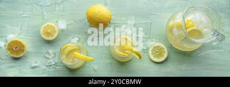 Limonade Panorama. Zitronenwassergetränk mit Eis. Zwei Gläser und ein Krug auf blauem Hintergrund, flach liegender Overhead-Shot. Entgiftungsgetränk. Frisch hausgemacht Stockfoto