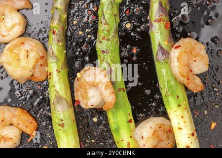 Spargel mit gewürzten Garnelen in einer gusseisernen Pfanne, gekrönt mit zerstoßenen roten Paprika Stockfoto