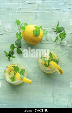 Limonade mit Minze. Zitronenwasser trinken mit Eis. Zwei Gläser auf blauem Hintergrund, über dem Kopf flacher Lay-Shot. Entgiftungsgetränk. Frischer hausgemachter Cocktail, Foo Stockfoto