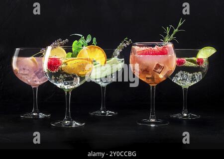 Ausgefallene Cocktails mit frischem Obst. Gin Tonic Drinks mit Eis auf einer Party, auf schwarzem Hintergrund, eine Vielfalt Stockfoto