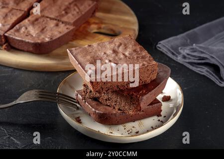 Schokoladenbrownie, einfacher Kaffeekuchen, auf schwarzem Schiefergrund, ein Stapel Scheiben, Lebensmittelfotografie Stockfoto