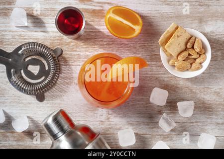 Orange Cocktails und ein Shaker, mit einem Jigger campari und Eis, über dem Kopf flache Lay-Shot auf hölzernem Hintergrund, Lebensmittelfotografie Stockfoto
