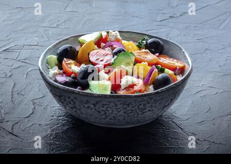 Griechischer Salat. Frische Tomaten und Gurken, Paprika und Fetakäse, Zwiebeln und Oliven. Bio-Sommernahrung, gesunde Ernährung, auf schwarzem Schieferhintergrund Stockfoto