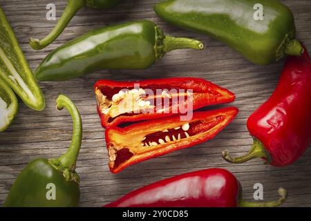 Eine Übersicht über ganze und geschnittene rote und grüne Paprika auf Holz Stockfoto