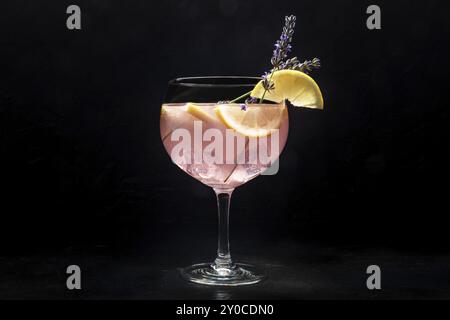 Schicker Cocktail mit frischem Obst. Gin Tonic Drink mit Eis auf einer Party, auf schwarzem Hintergrund. Alkohol mit Lavendel und Zitrone, Lebensmittelfotografie Stockfoto