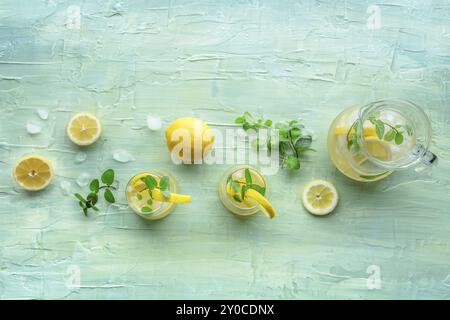 Limonade mit Minze. Zitronenwasser trinken mit Eis, zwei Gläser und ein Krug auf blauem Hintergrund. Entgiftungsgetränk. Frisch hausgemacht Stockfoto