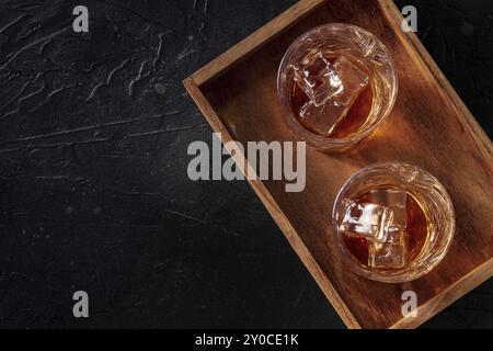 Whiskey in Gläsern mit Eis. Bourbon Whisky auf Felsen auf schwarzem Schiefergrund, flache Lay-Shot mit Kopierraum, Lebensmittelfotografie Stockfoto