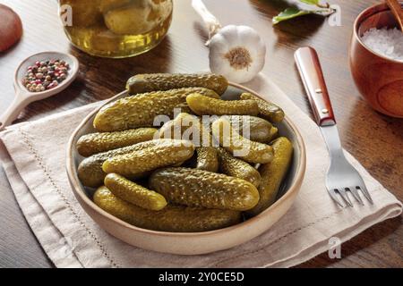 Eingelegte Gurken mit Salz, Pfeffer, Knoblauch und Lorbeerblatt. Fermentierte Lebensmittel. Hausgemachte Gurken in Dosen auf rustikalem Holzgrund Stockfoto