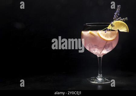 Schicker Cocktail mit frischem Obst. Gin Tonic Drink mit Eis auf einer Party, auf schwarzem Hintergrund. Alkohol mit Lavendel und Zitrone, mit einem Platz für Tex Stockfoto