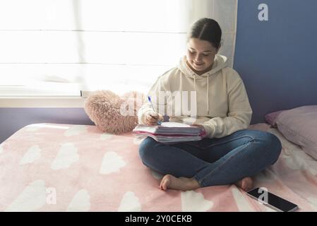 Junge kaukasische Frau, die auf ihrem Bett sitzt und konzentriert studiert. Lernumgebung und Ruhe zu Hause, tarragona, spanien Stockfoto