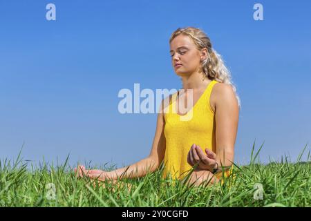 Junge blonde Holländerin meditieren in der Natur mit blauen Himmel Stockfoto