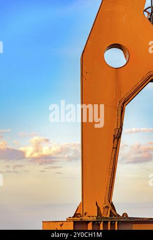 Detail der Große der alte Kran von unten mit blauem Himmel gesehen und einige Wolken im Hintergrund bei Sonnenuntergang Stockfoto