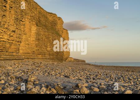 Die Steine und die Klippen von Llantwit Major Strand in der Abendsonne mit einigen Wolken über die Klippen, South Glamorgan, Wales, Großbritannien Stockfoto