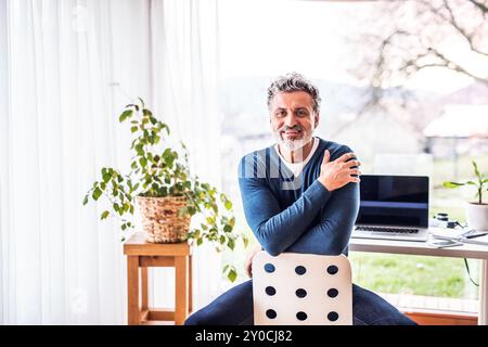 Homeoffice für einen schönen Mann. Mann, der rückwärts auf dem Stuhl sitzt. Telearbeit. Stockfoto