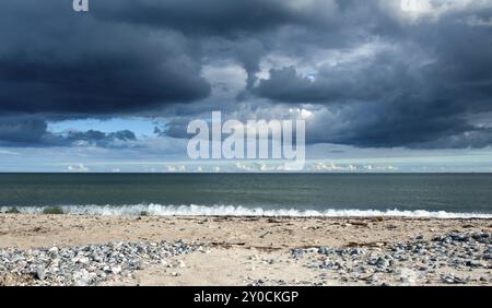 Blick über das Meer bei einem nahenden Wetterwechsel. Blick über einen einsamen Sandstrand mit Cumulonimbus-Sturmwolken, die sich über dem Ozean sammeln Stockfoto