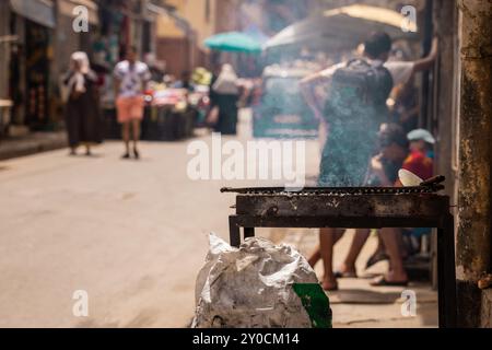 Kohlegrill wird auf den Marktstraßen von Oran, Algerien, angezündet. Seitenansicht eines kommerziellen Grills auf einem Markt im arabischen Land. Ein Sack Kohle daneben, Stockfoto